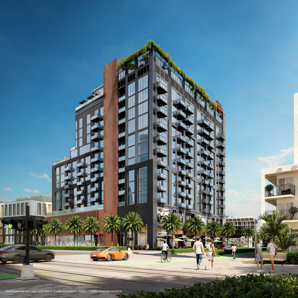 A daytime architectural rendering of The Rider Residences in Wynwood, Miami. The modern 12-story building features a mix of black brick and glass with a prominent copper-colored vertical beam. Pedestrians walk along a sunny, palm-lined street in the foreground where an orange sports car and a bicyclist are also visible. The sky is a clear, bright blue.