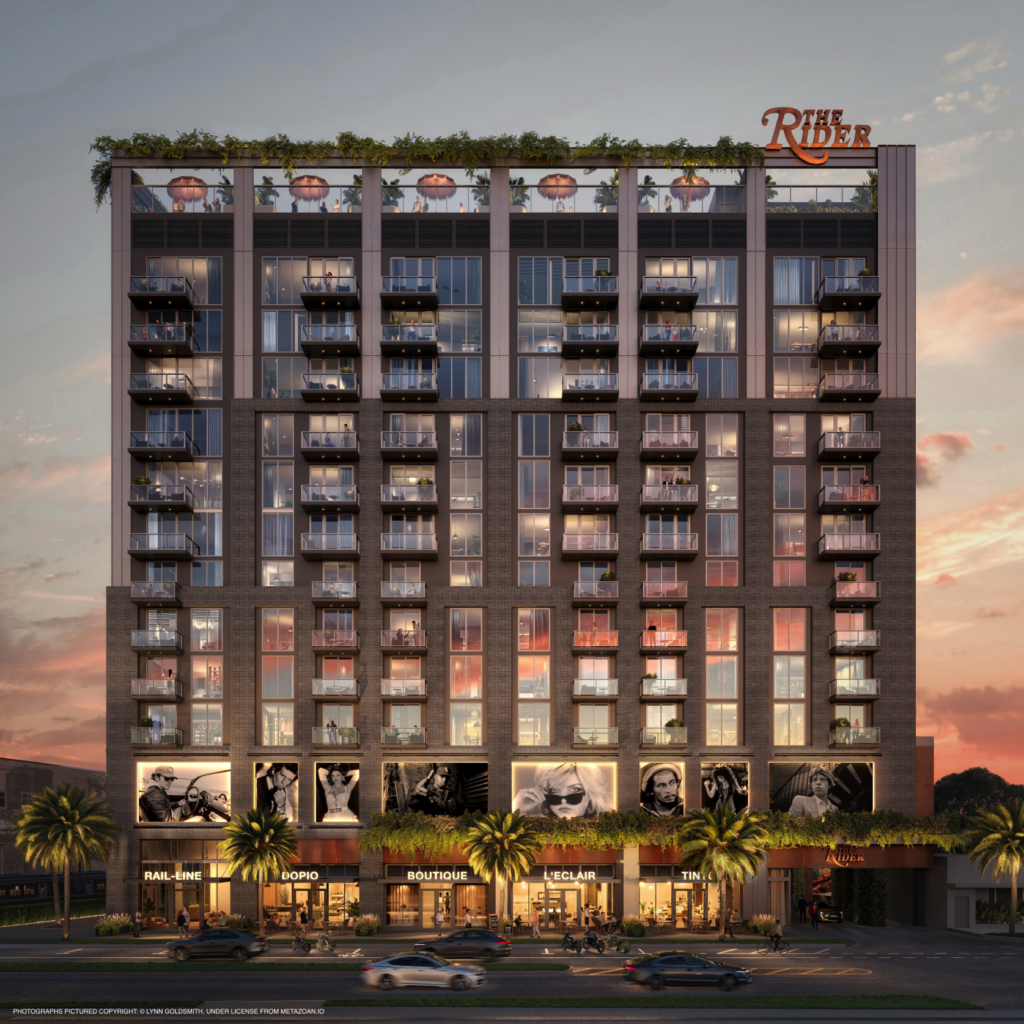 A dusk architectural rendering of The Rider Residences in Wynwood, Miami. The 12-story building features a dark grey and brick industrial facade with glowing glass balconies. The ground floor is lined with illuminated retail shops and features large-scale black-and-white rock-n-roll photography. On the rooftop, a lit-up lounge area sits beneath a large neon sign that reads "The Rider" against a pink sunset sky.