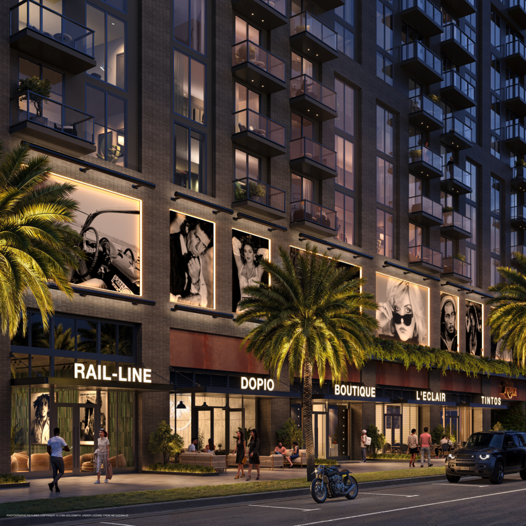 A dusk rendering of the ground-floor retail promenade at The Rider Residences in Wynwood. The scene features glowing storefronts with names like "Rail-Line," "Dopio," and "Boutique." Above the shops, massive backlit black-and-white celebrity portraits are embedded into the building's brick exterior. Pedestrians walk along the sidewalk, and a vintage motorcycle is parked near a modern SUV on the street.
